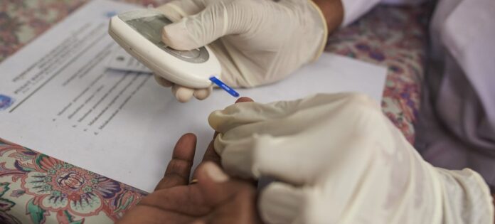 Profissional de saúde verifica o nível de açúcar no sangue de uma mulher em um centro de saúde comunitário no distrito de Jayapura, Indonésia.